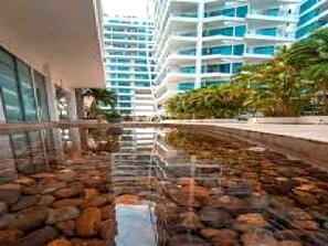 A modern building with a reflective water feature in front.