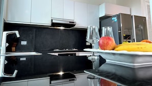 A modern kitchen with white cabinets, a black countertop, and stainless steel appliances.