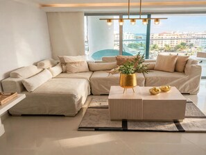 A modern living room with a sectional sofa, a coffee table, and a view of the city.