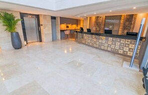 A hotel lobby with a reception desk, a large potted plant, and an elevator. - Luxurious 3-bedroom Apartment With Shared Pool in Bolívar (Cartagena)
