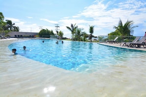 A swimming pool with clear water, surrounded by palm trees and lounge chairs. - Luxurious 3-bedroom Apartment With Shared Pool in Bolívar (Cartagena)