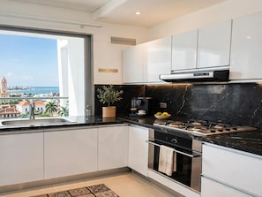 A modern kitchen with a view of the city, a coffee machine, and a stove. - Luxurious 3-bedroom Apartment With Shared Pool in Bolívar (Cartagena)