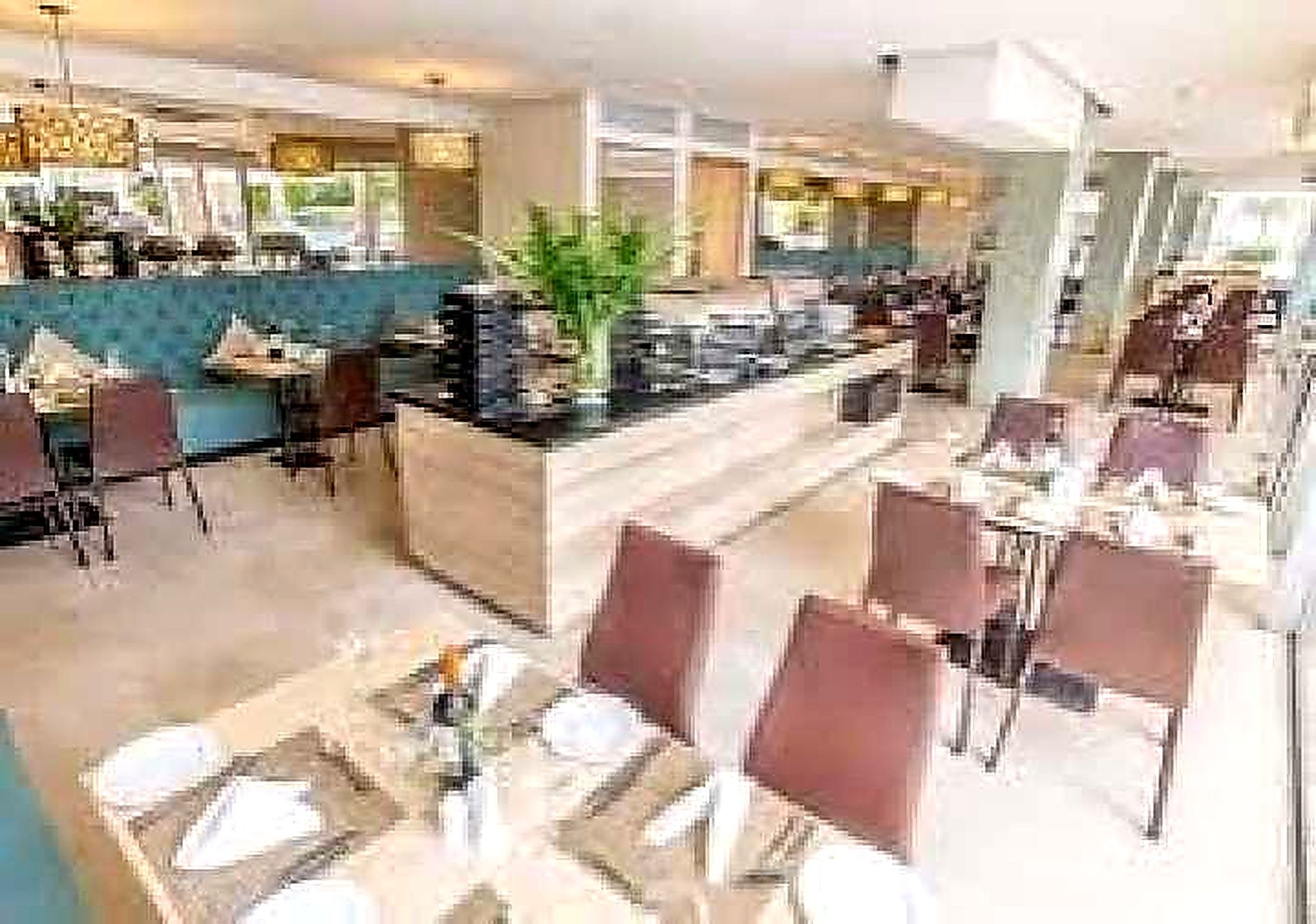A hotel lobby with a central counter, seating area, and a large window.