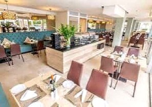 Un vestíbulo de hotel con mostrador central, zona de estar y un amplio ventanal.