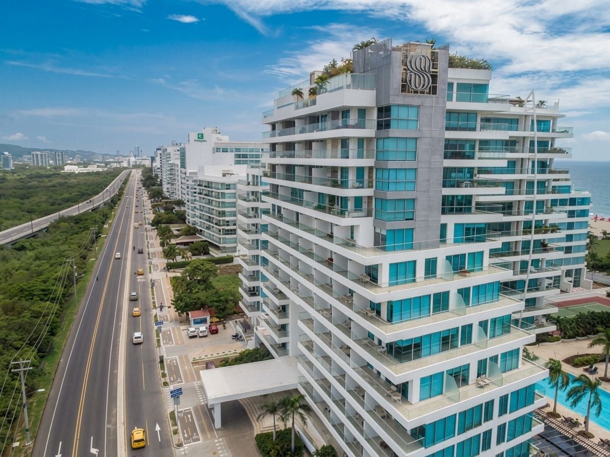 Un hotel de varios pisos con balcones, una piscina y vistas al océano.