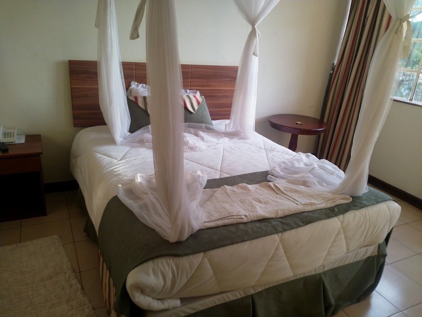 A bed with a canopy, a bedside table with a phone, and a small round table.
