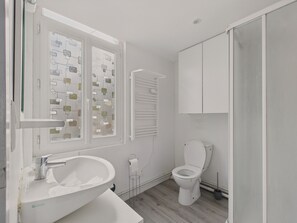 Et moderne badeværelse med en hvid vask, toilet og bruseafdeling.