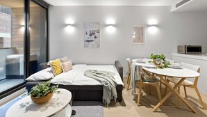 Une chambre à coucher moderne avec un lit, une table de chevet et un coin repas comprenant une table et des chaises.