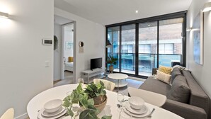 Un salon moderne avec un coin repas, de grandes fenêtres et un canapé gris.