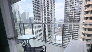 Un balcón con una mesa y sillas, con vista a un paisaje urbano de edificios altos.