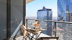 Ein Balkon mit Tisch für zwei Personen, mit Blick auf eine Skyline moderner Gebäude.