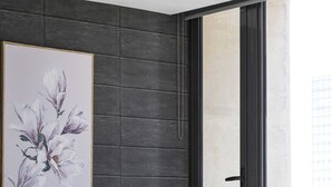 A modern bedroom with a large bed, a dark wall paneling, a window with a view, and a framed floral artwork. - A Cozy 2BR Apt on Spencer St With Free Parking (Melbourne)