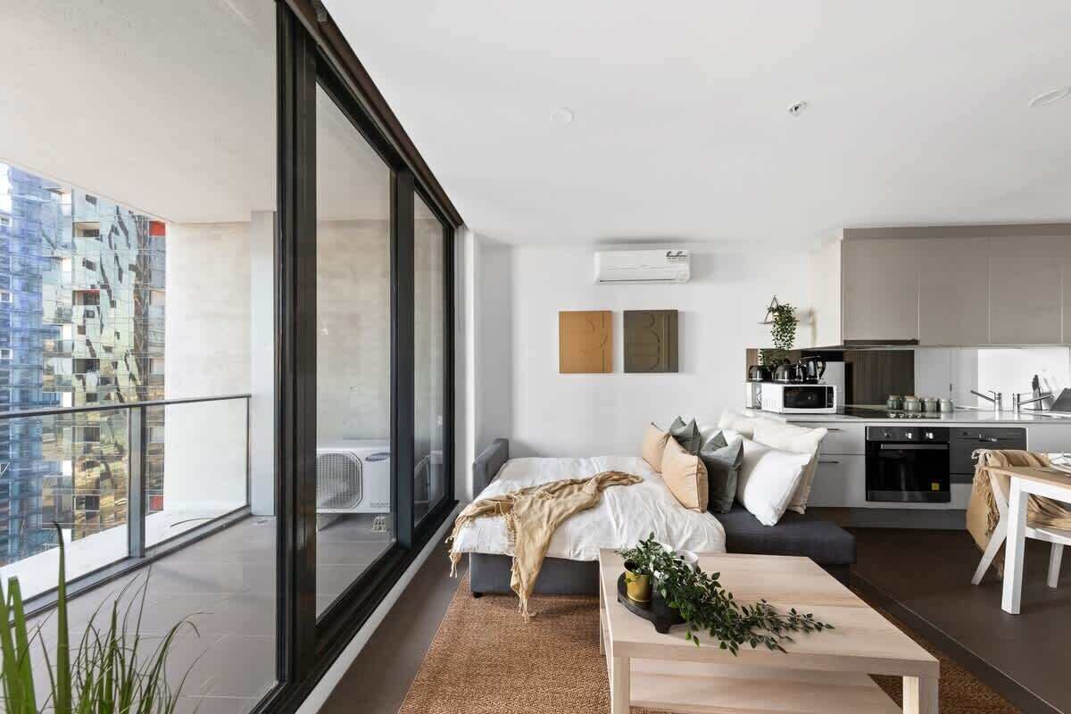 A modern apartment with a balcony, a living room with a sofa and coffee table, a kitchen, and a dining area.