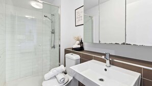 Une salle de bain moderne avec une douche à parois de verre, un lavabo blanc et des toilettes.