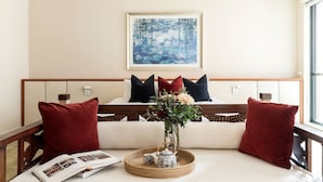 A cozy room with a bed, a bedside table with a vase of flowers, and a painting on the wall. - Stylish & Cozy 4BR Retreat With Free Parking (Melbourne)