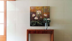 A wooden console table with a vase of flowers and a painting of lotus flowers on the wall behind it. - Stylish & Cozy 4BR Retreat With Free Parking (Melbourne)