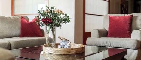 Una sala de estar con dos sofás, una mesa de centro y un jarrón con flores.