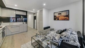 Eine moderne Wohnung mit Küche, Essbereich und Schlafzimmer mit großem Bett und Stadtbildgemälde.