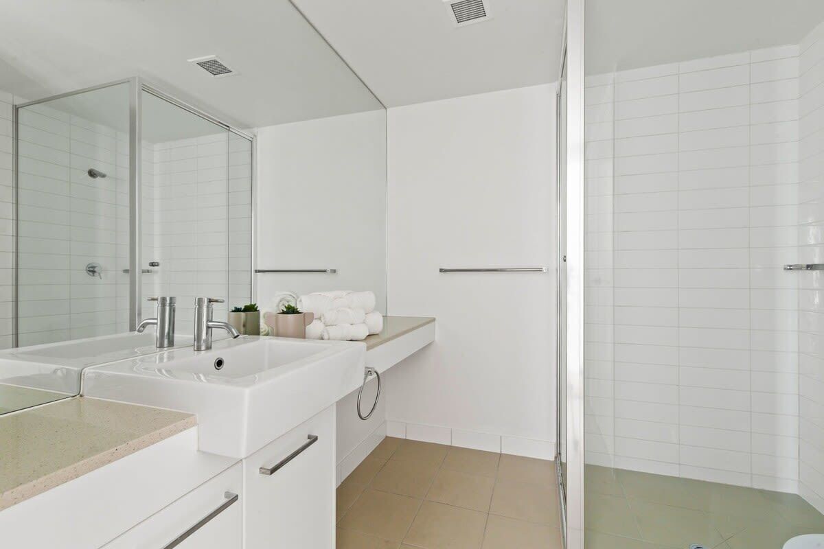 Un baño moderno con lavamanos doble, cabina de ducha de vidrio y toallero.