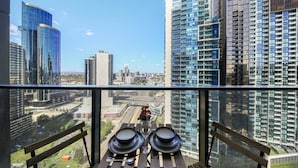 A balcony with a table set for two, overlooking a cityscape with modern high-rise buildings.