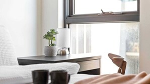 A neatly arranged bedroom with a bed, bedside table, lamp, potted plant, and two mugs. - A 2BR Apt in Parkville Near the Melbourne Zoo (Melbourne)