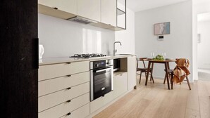 A modern kitchen with built-in appliances, a dining area with a table and chairs, and a minimalist design. - A 2BR Apt in Parkville Near the Melbourne Zoo (Melbourne)
