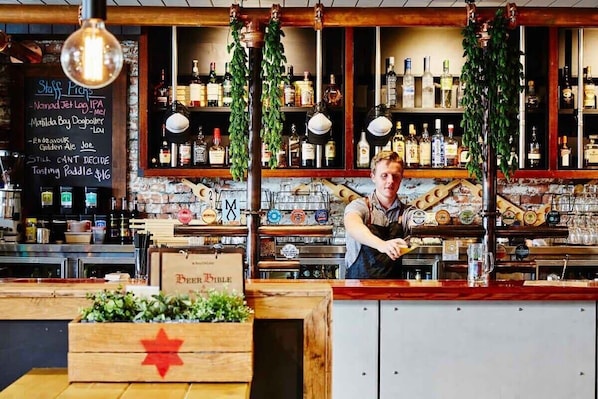 A bar with a chalkboard menu, wooden bar counter, and various bottles.