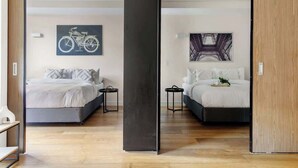 Une chambre moderne avec deux lits, un plancher en bois et des œuvres d’art accrochées aux murs.