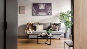 Un salon moderne avec un canapé gris, une table basse et une grande plante en pot.