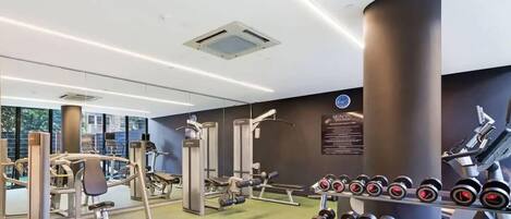 A modern gym with various exercise equipment, including weight machines and dumbbells.