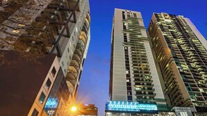 Un immeuble moderne de grande hauteur, doté d’une façade en verre et de nombreux balcons.