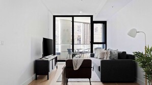 Una sala de estar moderna con un sofá, un televisor, una mesita auxiliar y una lámpara de pie.