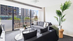 Una sala de estar moderna con un sofá gris, una mesa de centro y una gran planta en maceta.