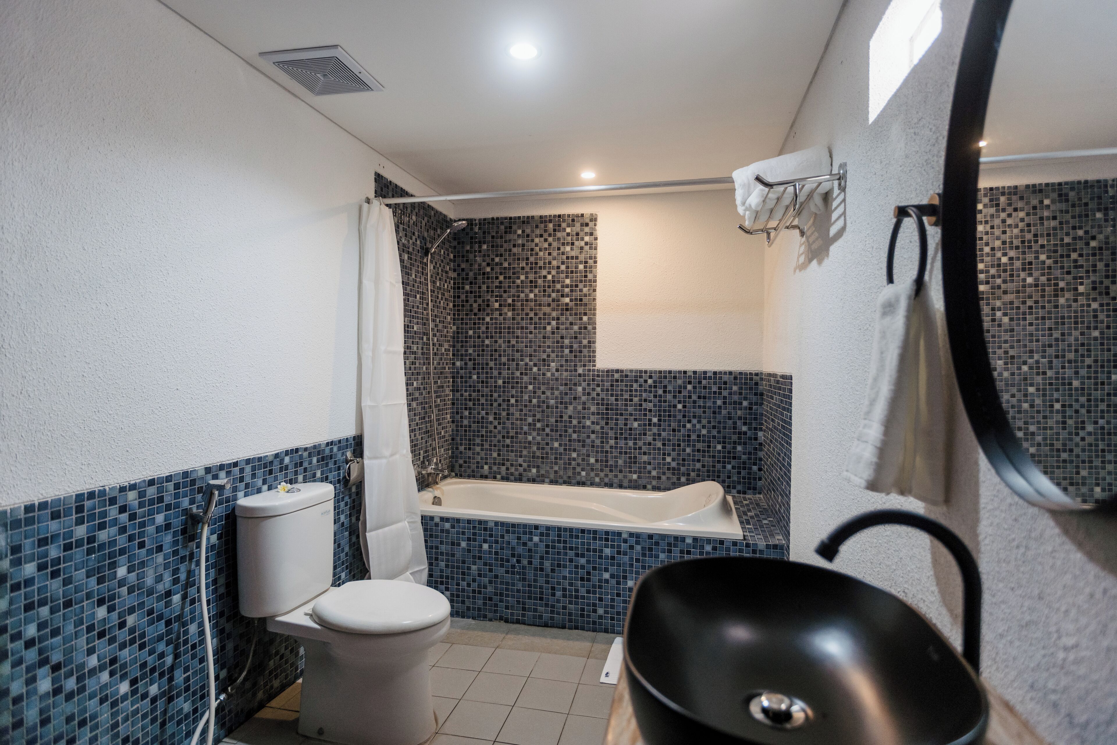 A bathroom with a toilet, bathtub, and a black sink.