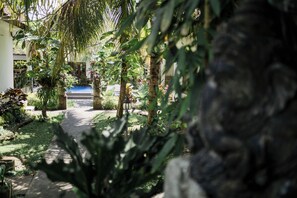 A garden pathway with tropical plants and a blue pool in the background. - Sundhara View Ubud (Sukawati)