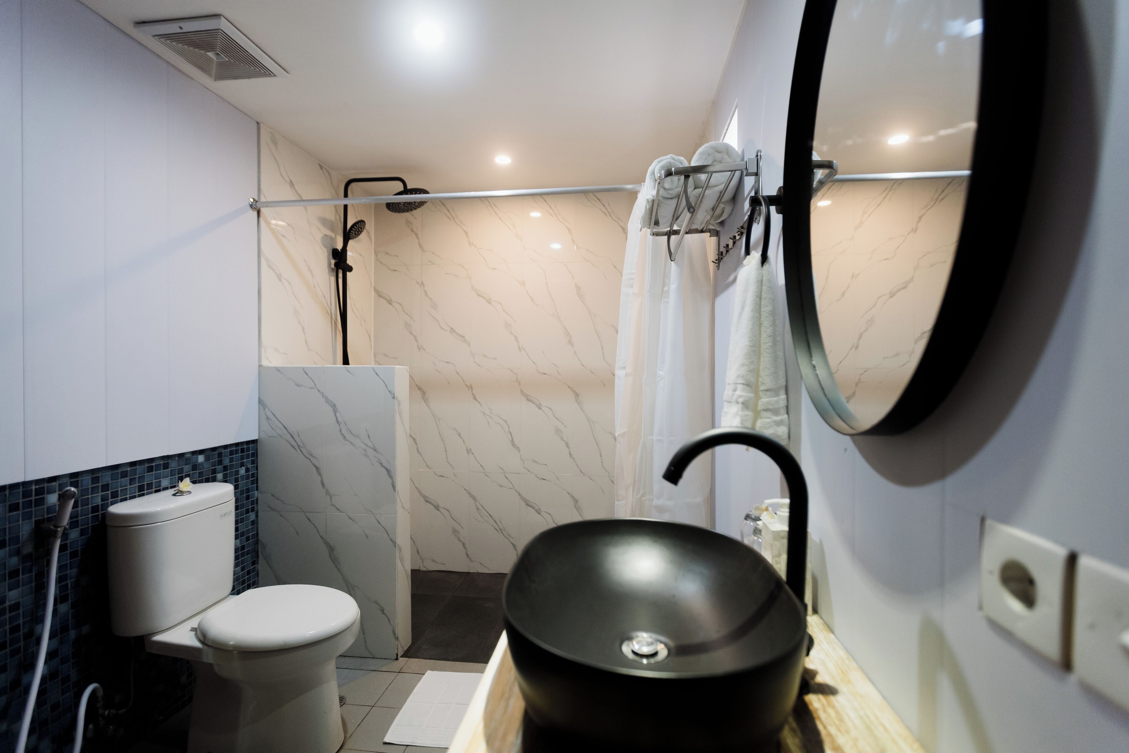 Et moderne badeværelse med toilet, vask og bruser.