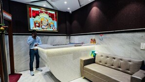 Un área de recepción con piso de mármol, un sofá, un tapete rojo y un cuadro religioso enmarcado en la pared.