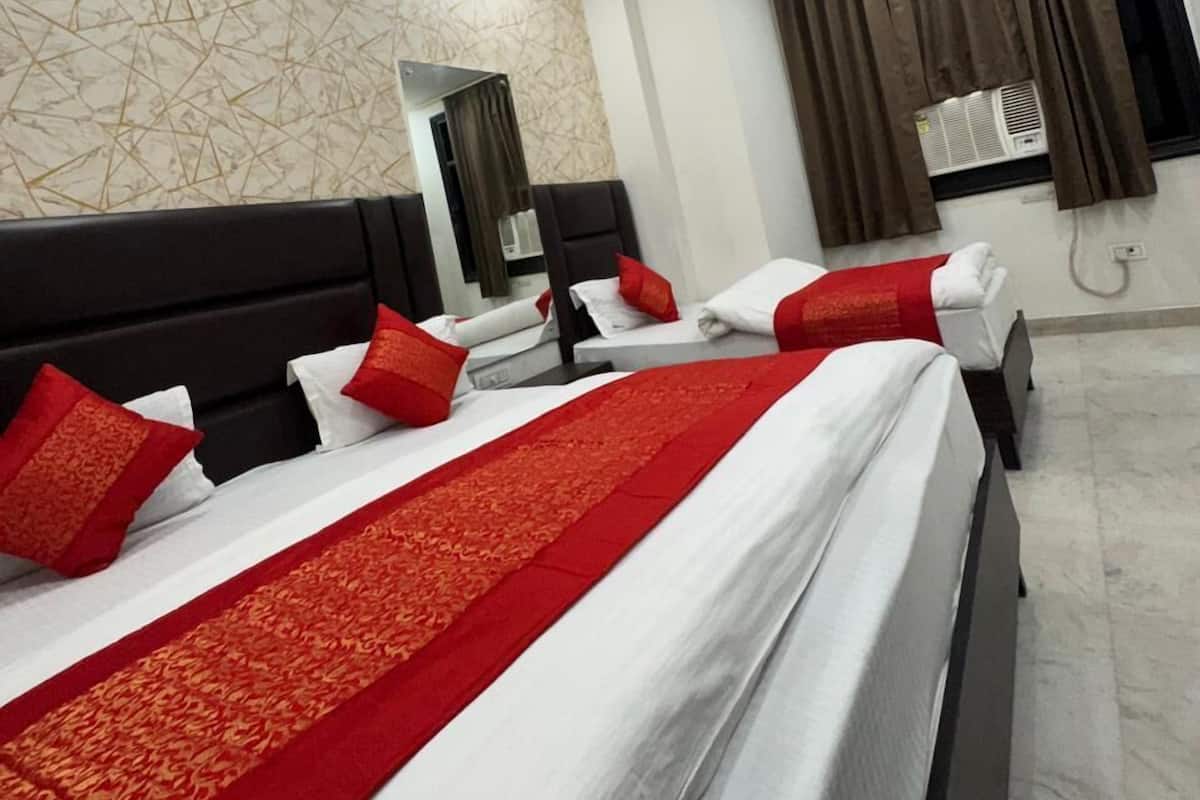 Habitación de hotel con tres camas, ventilador de techo y pared con diseño de mármol.