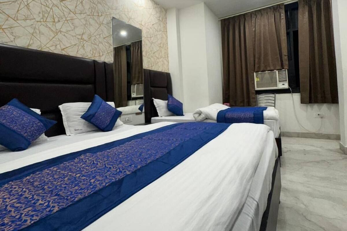 Habitación de hotel con una cama grande, ventilador de techo, aire acondicionado instalado en la pared y ventana con cortinas.