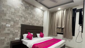 Un dormitorio moderno con una cama color café oscuro, ropa de cama blanca y detalles en tonos rosados.