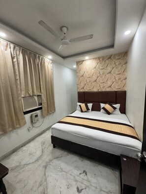 A modern bedroom with a marble floor, a bed with a brown headboard, beige curtains, and a ceiling fan.