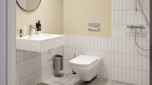 A modern bathroom with a white sink, a toilet, a mirror, and a shower.