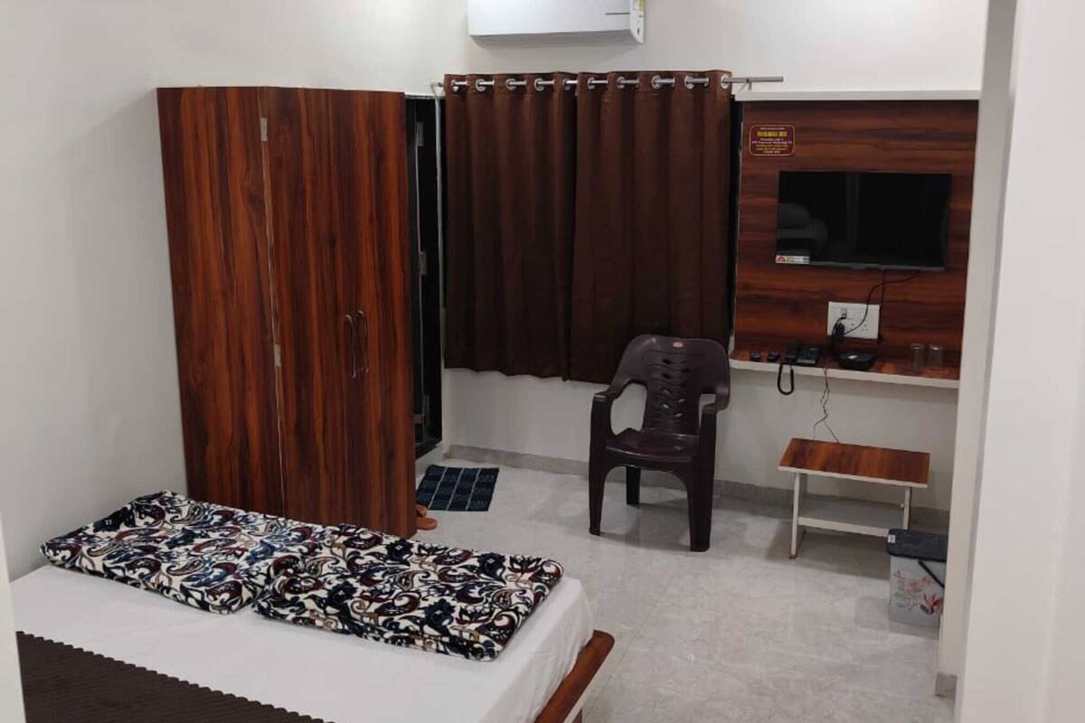 Ein Schlafzimmer mit Bett, Kleiderschrank, Schreibtisch, Stuhl und Fernseher.