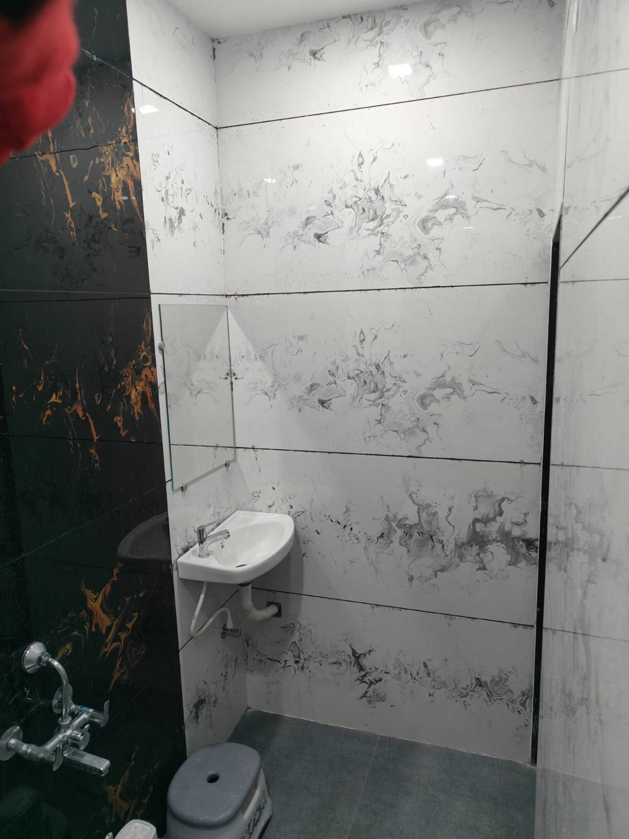 Ein Badezimmer mit einem weißen Waschbecken, schwarz-weißen Marmorwänden und einer Duschkabine.