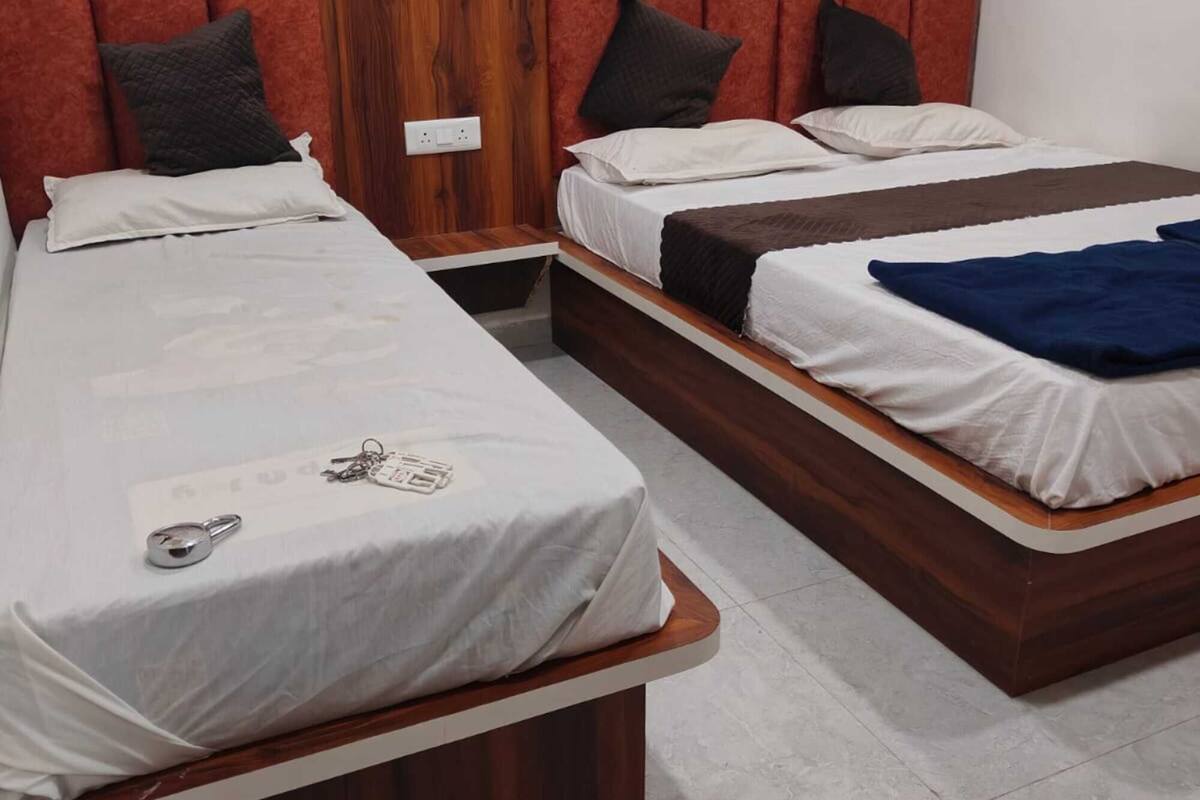 Ein Hotelzimmer mit zwei Betten, Holzkopfteilen und einem gefliesten Boden.