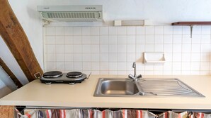 Cocina con estufa, pileta y salpicadero de azulejos blancos.