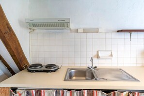 A kitchen with a stove, sink, and white tiled backsplash.