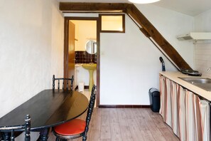 A dining area with a table and chairs, a kitchen with a sink and stove, and a staircase leading to an upper level. - Apartment 'Tamburine Xaharra' with Mountain View and Wi-Fi (Ainhoa)