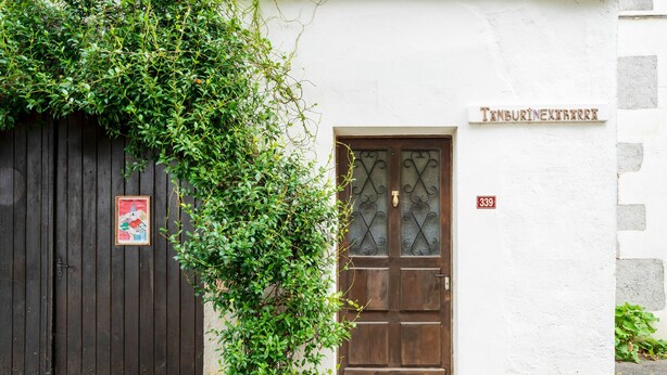 Un edificio con una puerta de madera oscura, una pared blanca y un cartel sobre la puerta.