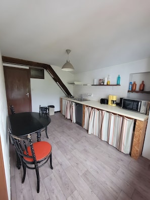 A compact kitchen with a dining table, chairs, and a microwave. - Apartment 'Tamburine Xaharra' with Mountain View and Wi-Fi (Ainhoa)